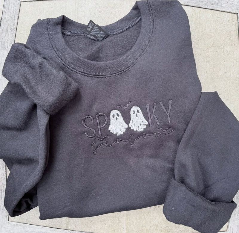Charcoal crewneck with SPOOKY in tone-on-tone letters, two white ghosts as the Os, and season in script below